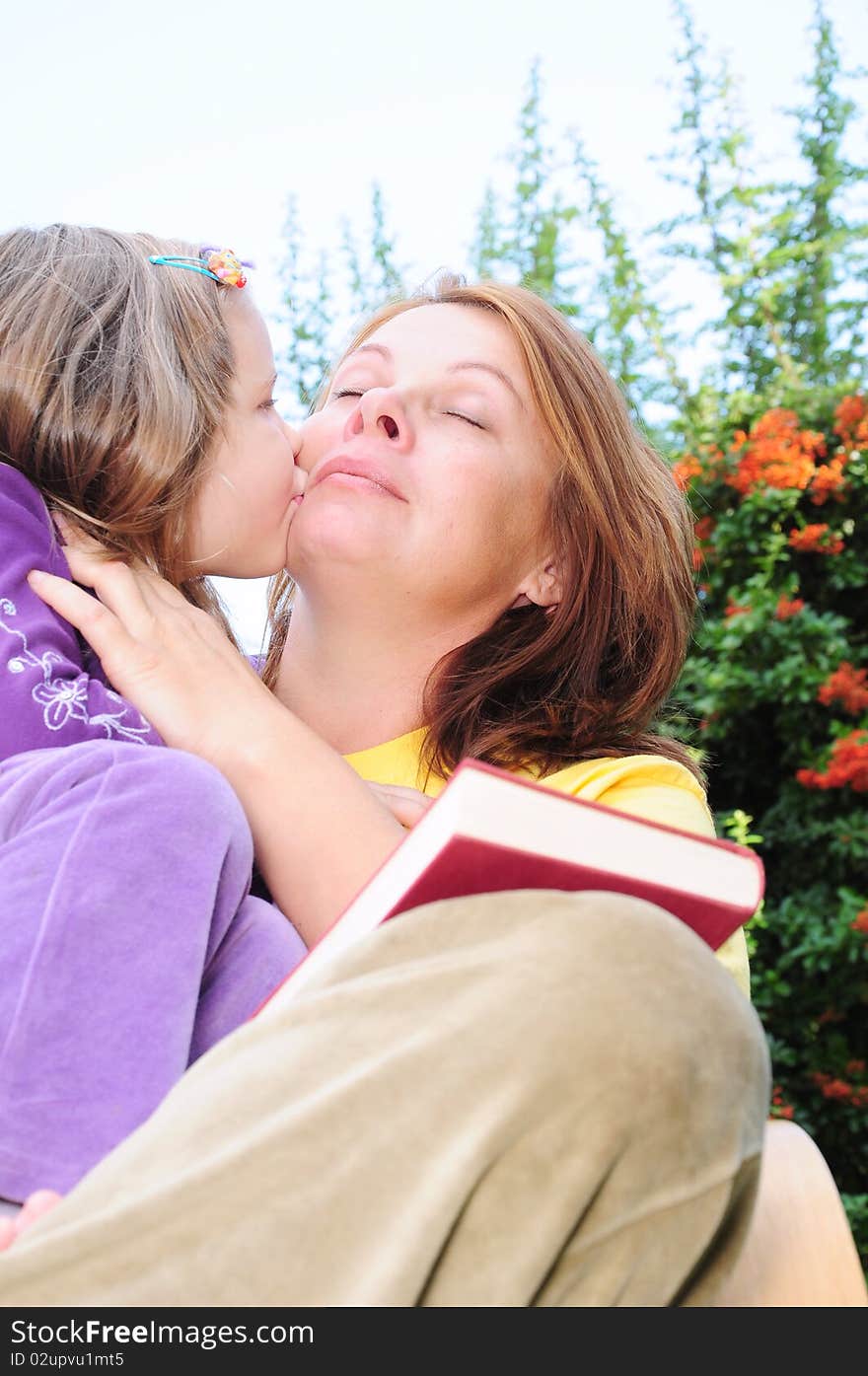 Kiss mother and daughter in the yard. Kiss mother and daughter in the yard