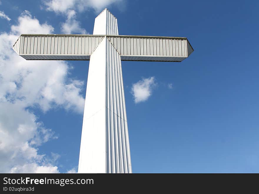 A massive white cross stands against a blue sky. Copy-space on the side for your message. A massive white cross stands against a blue sky. Copy-space on the side for your message.