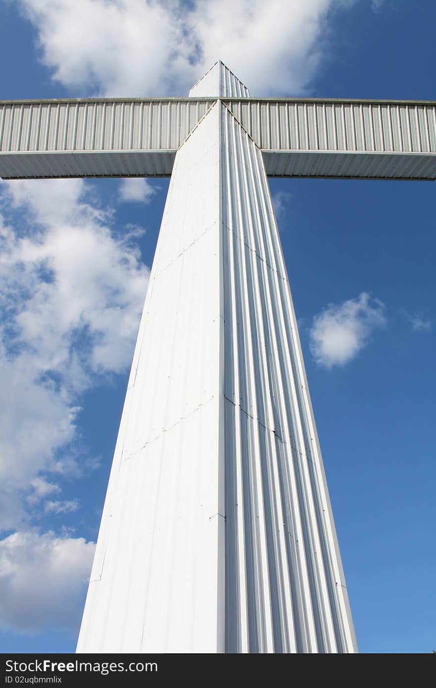 Massive white cross make of modern materials against clue sky. Massive white cross make of modern materials against clue sky.