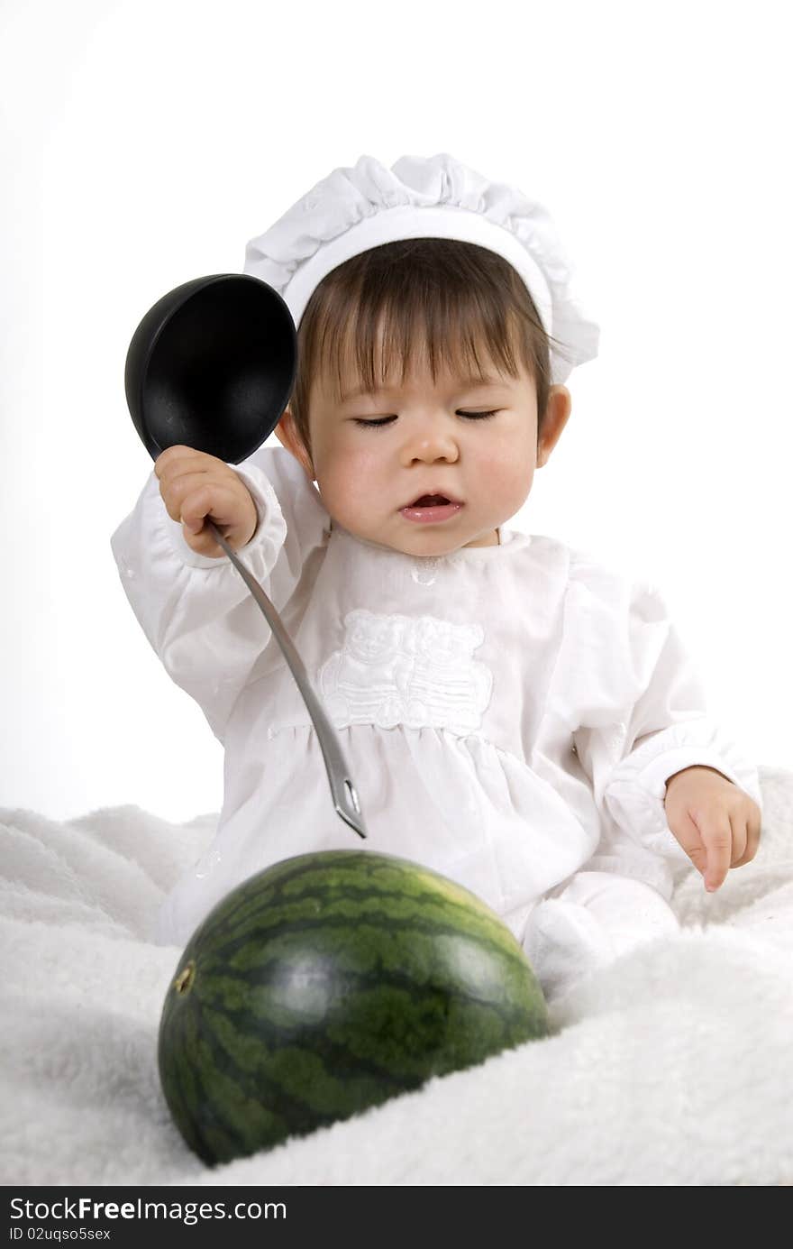 Little girl in the cook costume sitting with watermelon with ladle in hand. Little girl in the cook costume sitting with watermelon with ladle in hand