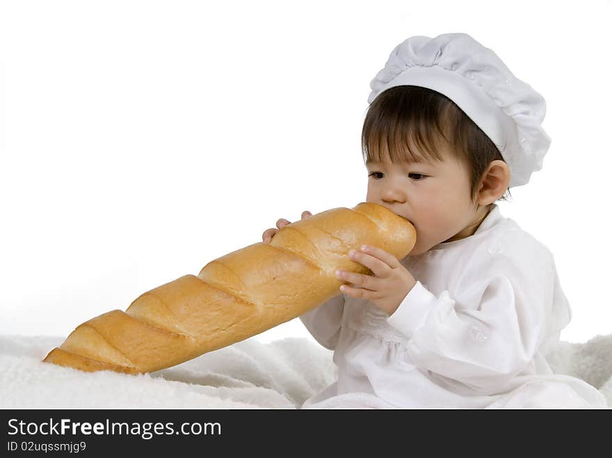 Cute baby in white cooking dress biting big baguette. Cute baby in white cooking dress biting big baguette