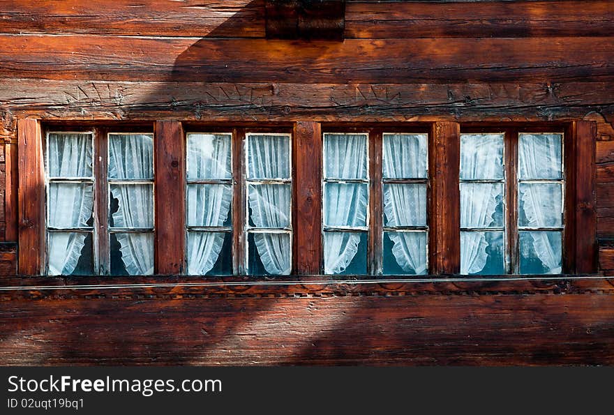 Row of four small windows in a traditional swiss wooden chalet