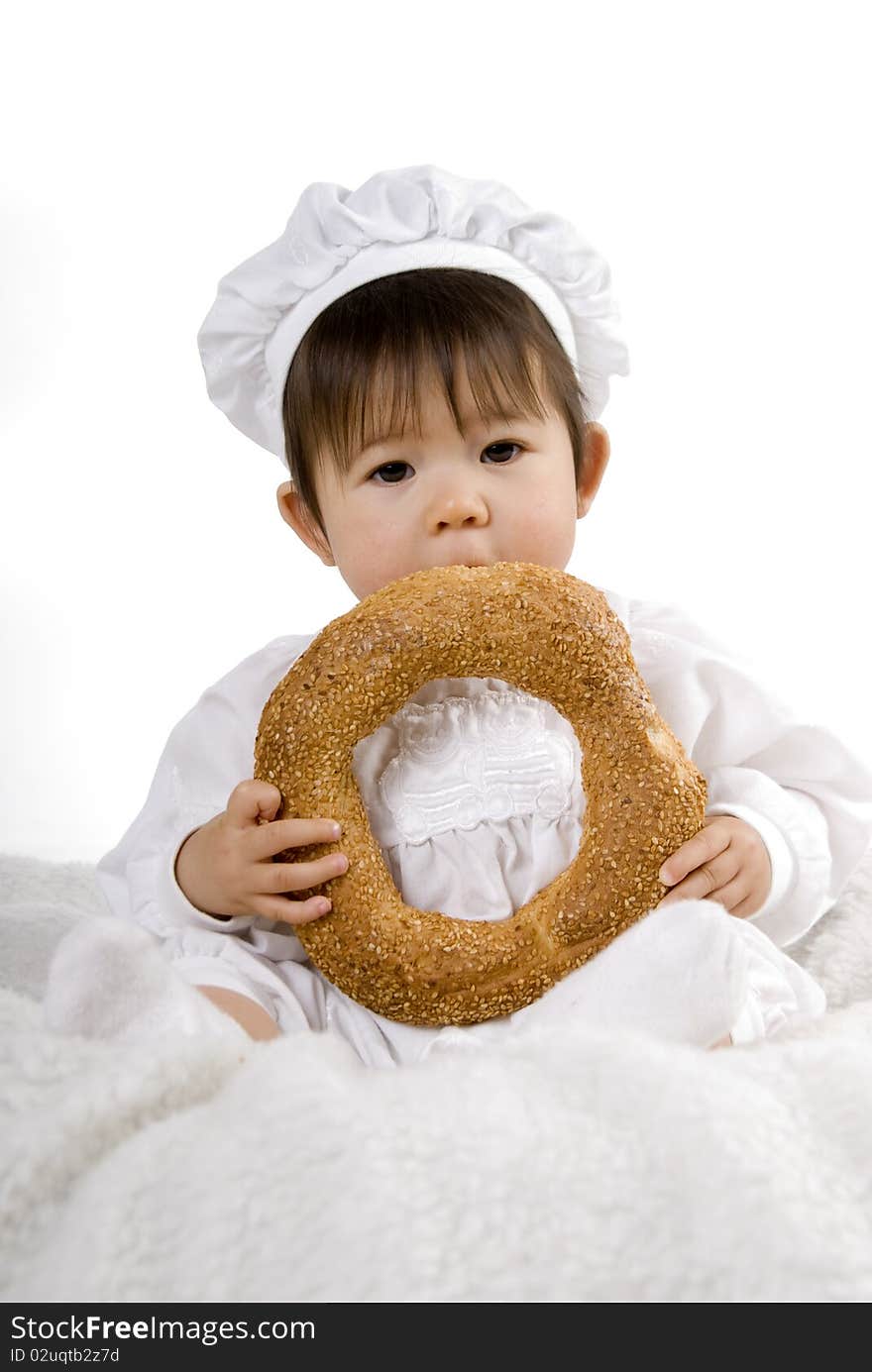 Little baby in chef dress sitting and eat bread. Little baby in chef dress sitting and eat bread