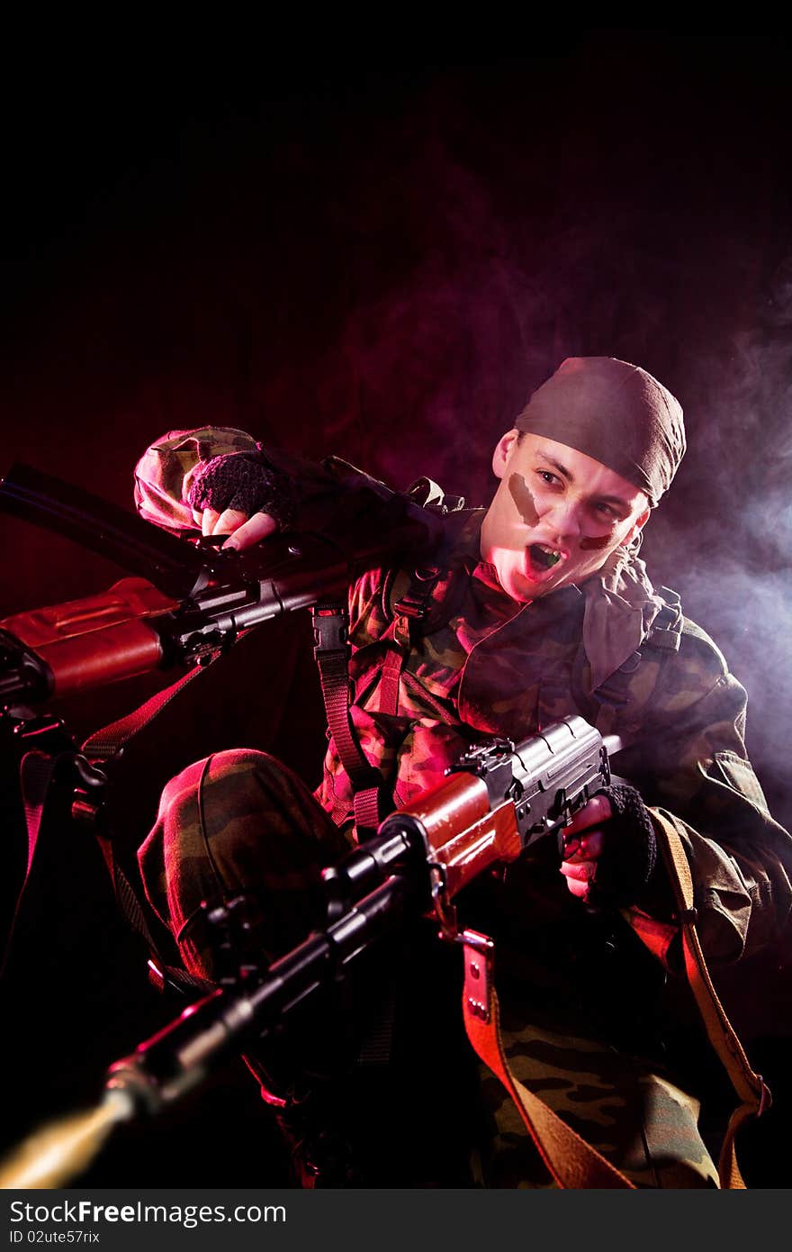 Screaming soldier shooting his enemies, studio shot over black background