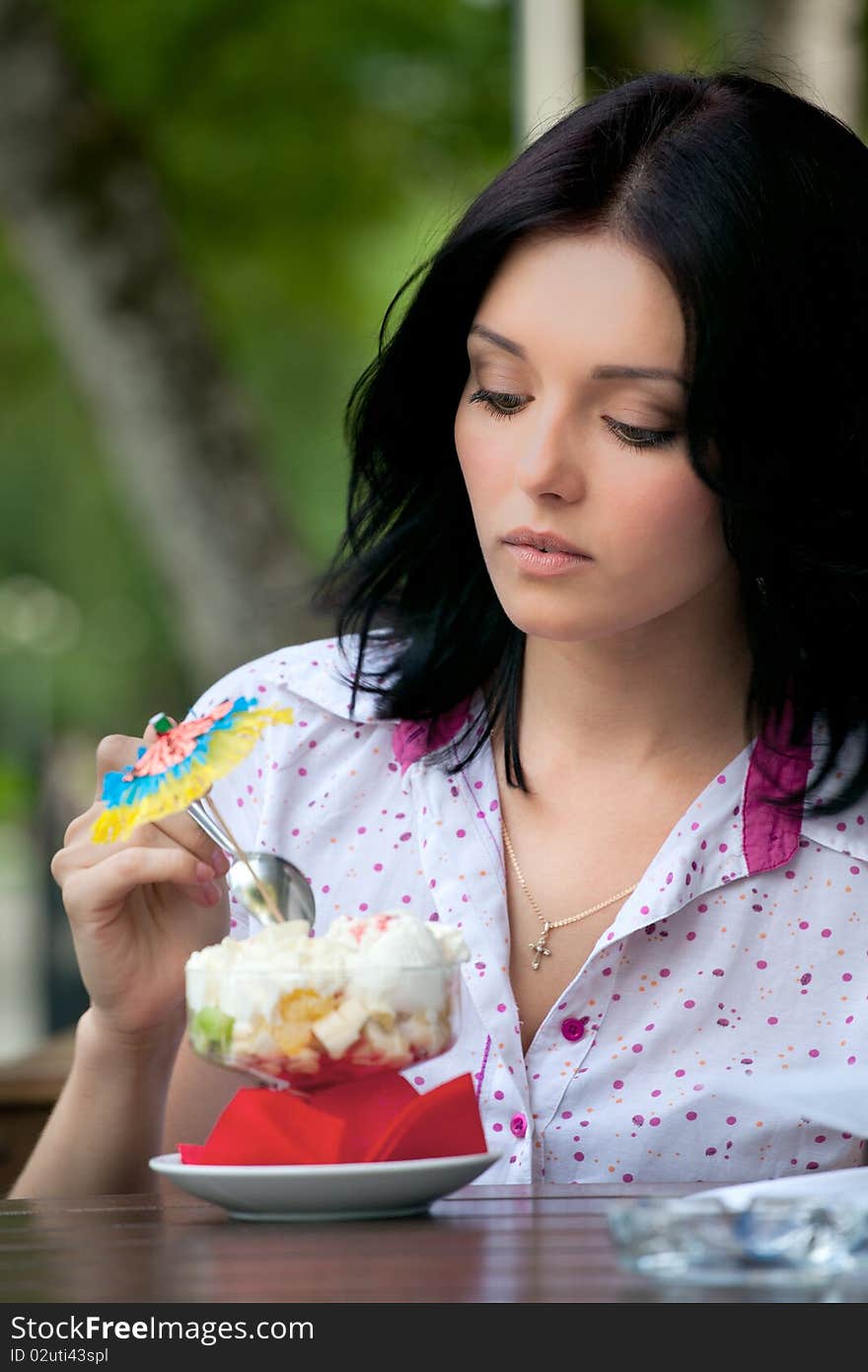 Young beautiful woman eating an ice cream in cafe. Young beautiful woman eating an ice cream in cafe