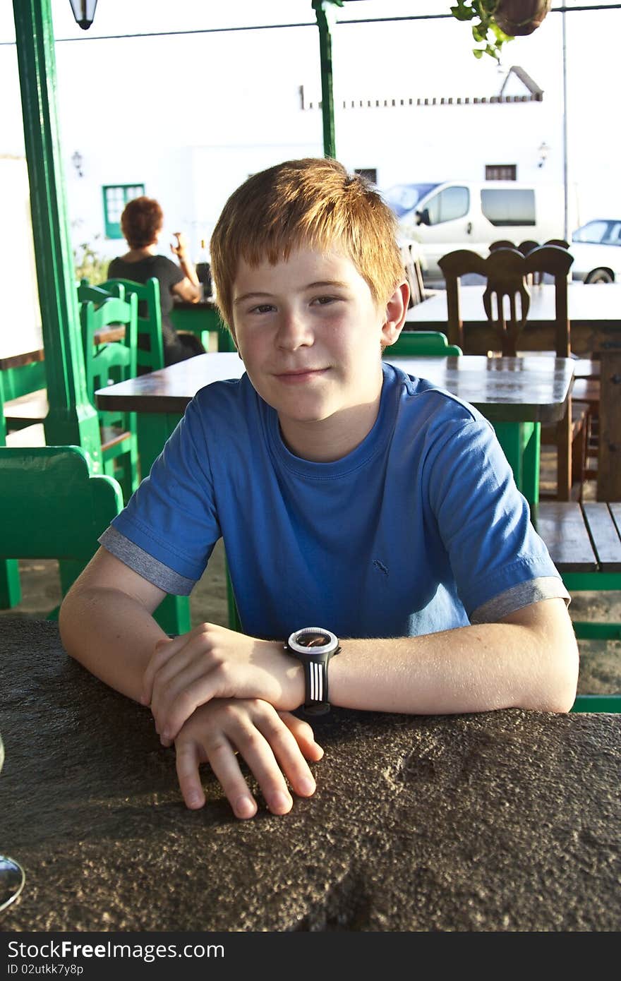 Young boy is sitting on a table in a restaurant