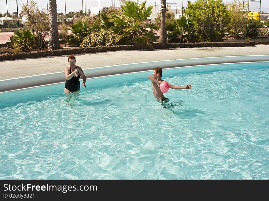 Mother and son are playing with ball in pool. Mother and son are playing with ball in pool