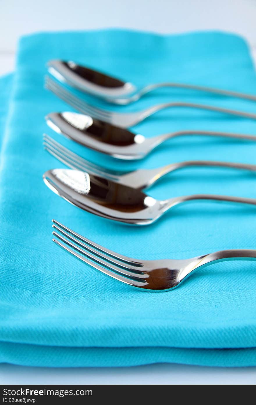 Cutlery forks and spoons on a blue napkin