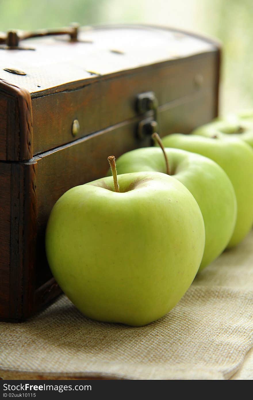 Green apples on the background of an old wooden chest