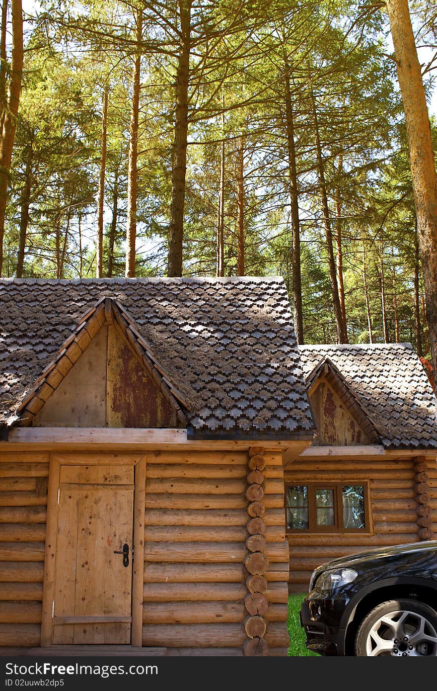 The car and small houses from pine logs camping in wood. The car and small houses from pine logs camping in wood