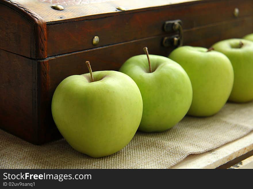 Green apples on the background of an old wooden chest