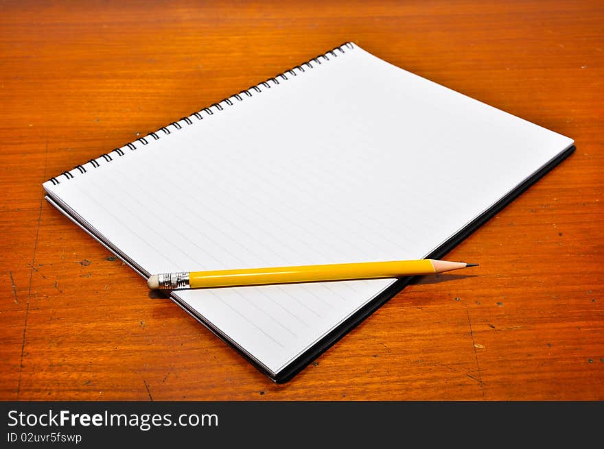 White Blank Notebook with yellow pencil on Wood Background