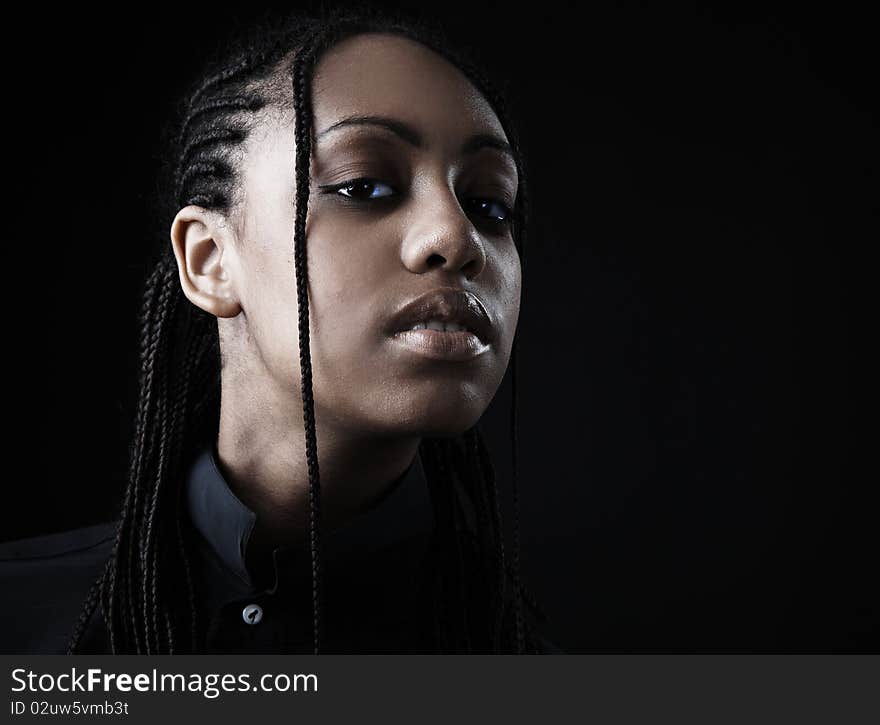 Portrait of a beautiful young black woman posing in black background.