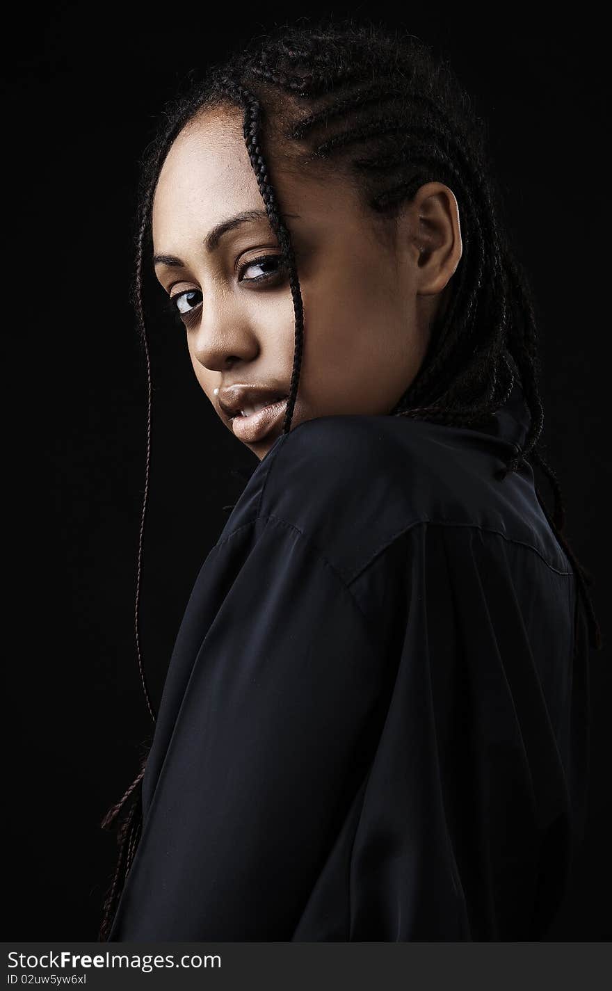 Portrait of a beautiful young black woman posing in black background.