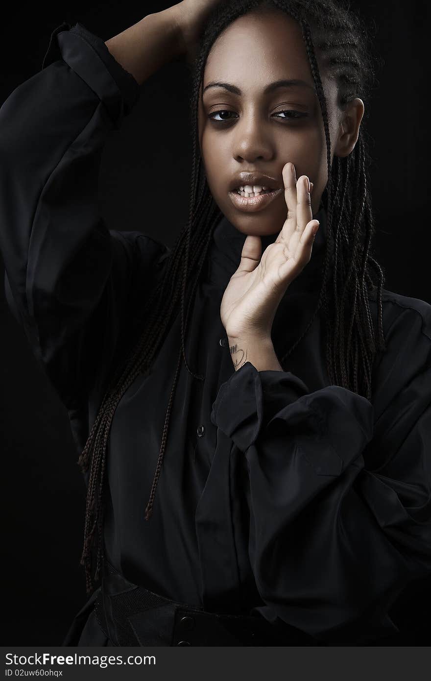 Portrait of a beautiful young black woman posing in black background.