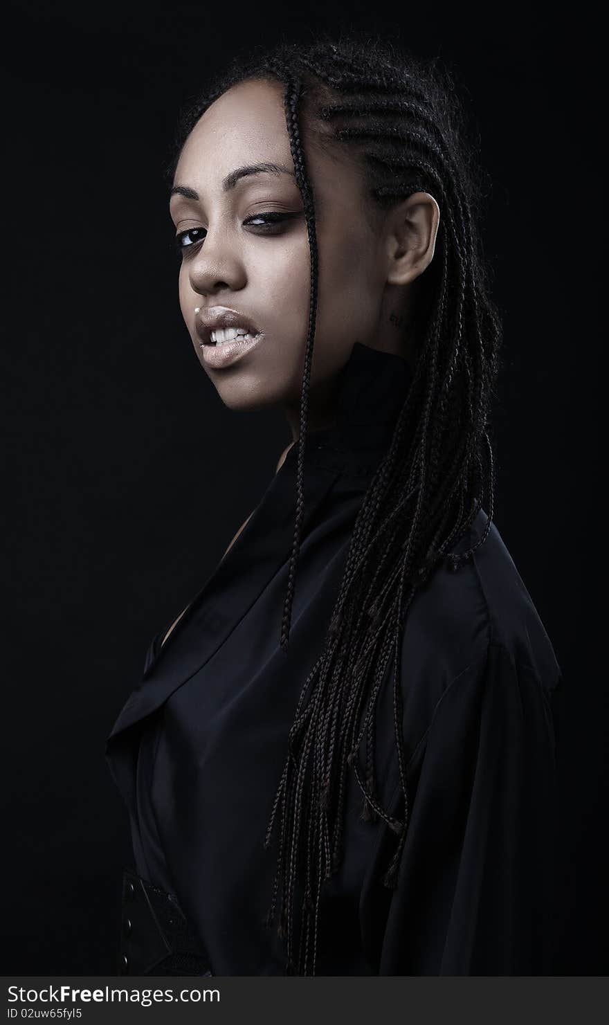 Portrait of a beautiful young black woman posing in black background.