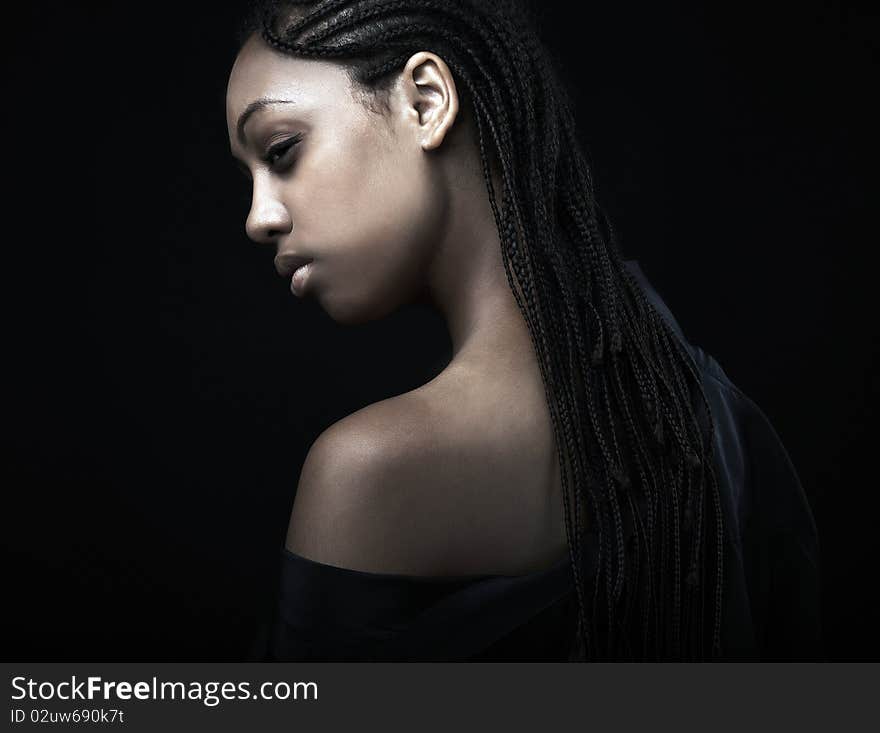 Portrait of a beautiful young black woman posing in black background.