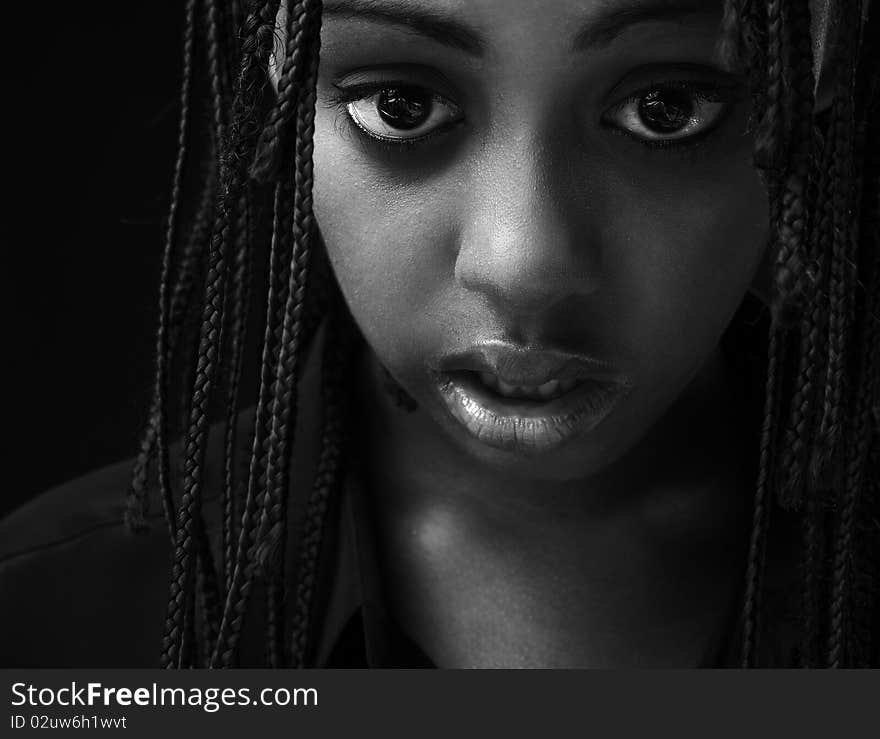 Portrait of a beautiful young black woman posing in black background.