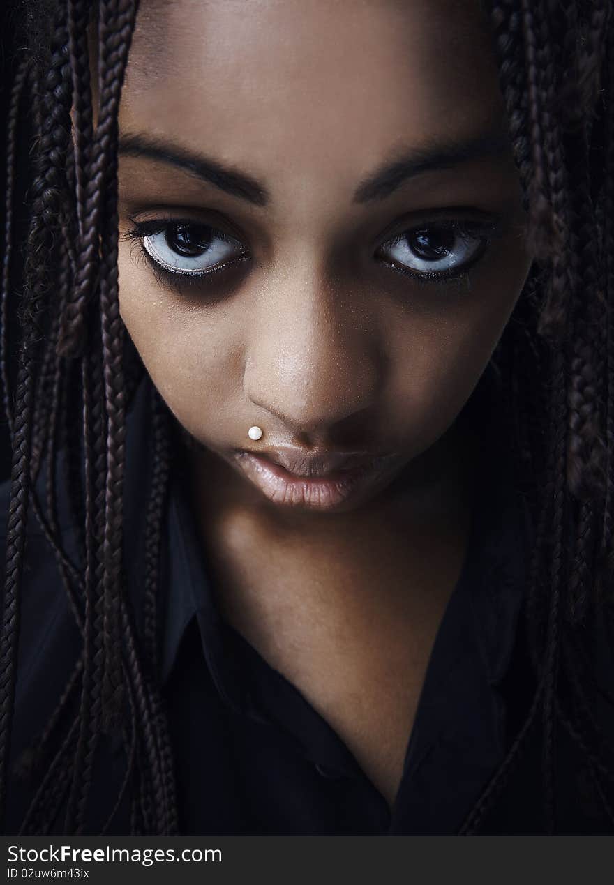 Portrait of a beautiful young black woman posing in black background.