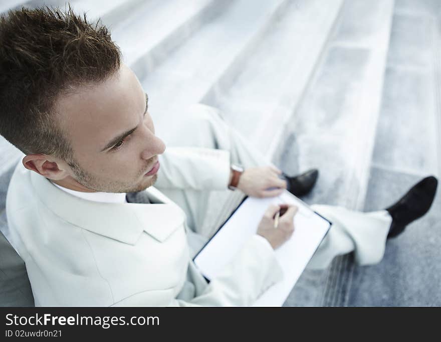 Handsome business man on the stairs reviewing his notes. Handsome business man on the stairs reviewing his notes