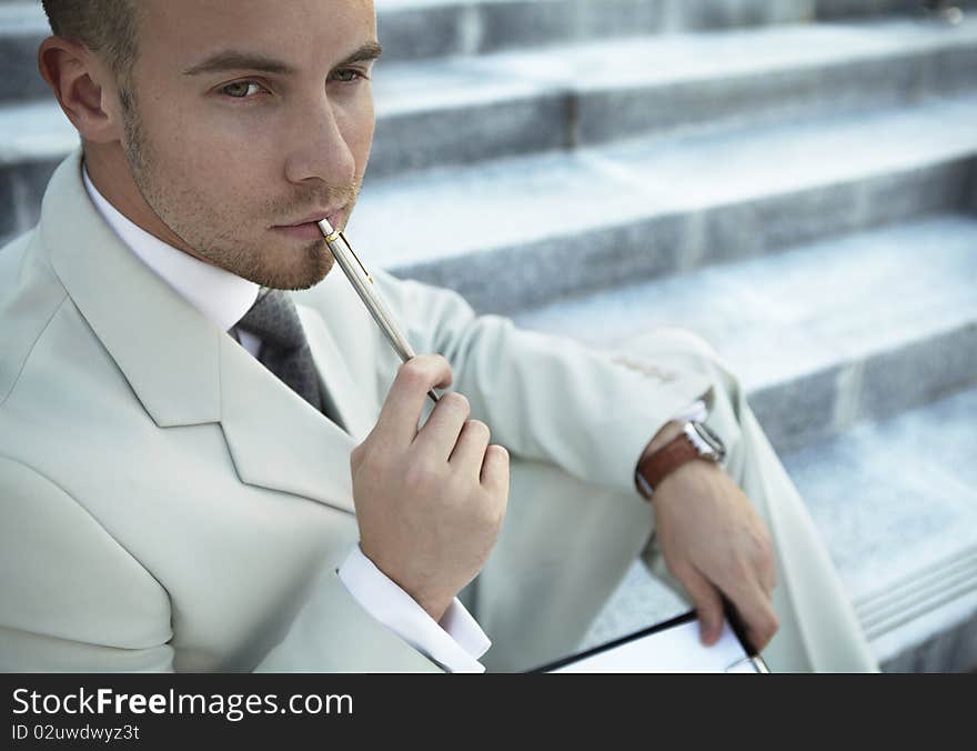 Handsome business man on the stairs reviewing his notes. Handsome business man on the stairs reviewing his notes