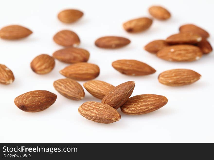 Almonds are scattered on a light surface.