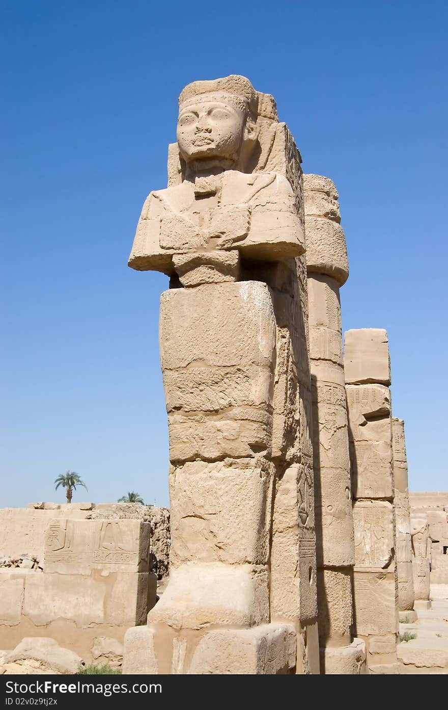 Ancient Pharaoh statue and column on backlighted sky background