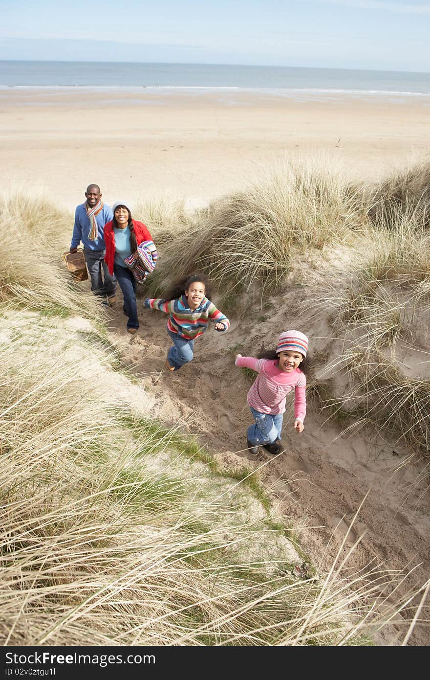 Family Walking Along Dunes On Winter Beach Smiling.