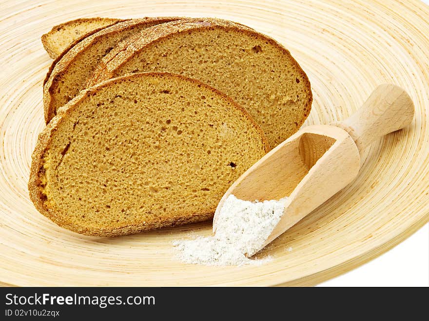 Rye bread on wooden plate and spoon of flour