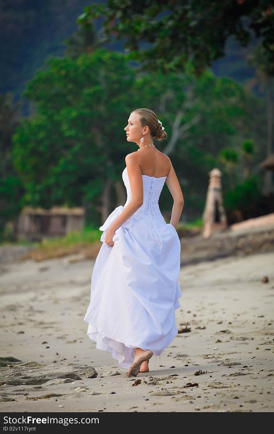 Bride walking along sea coast in the wedding dress