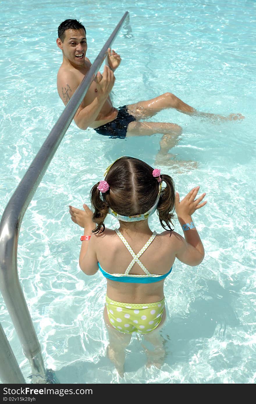 Father and daughter are playing in pool.