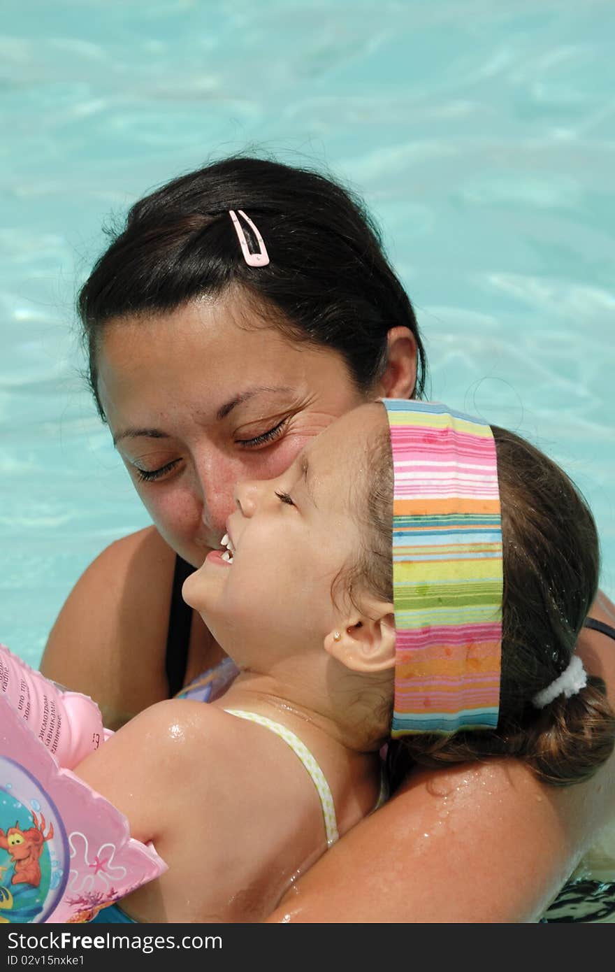 Happy woman and child on vacation. They are swimming in pool while laughing and looks very happy. Happy woman and child on vacation. They are swimming in pool while laughing and looks very happy.