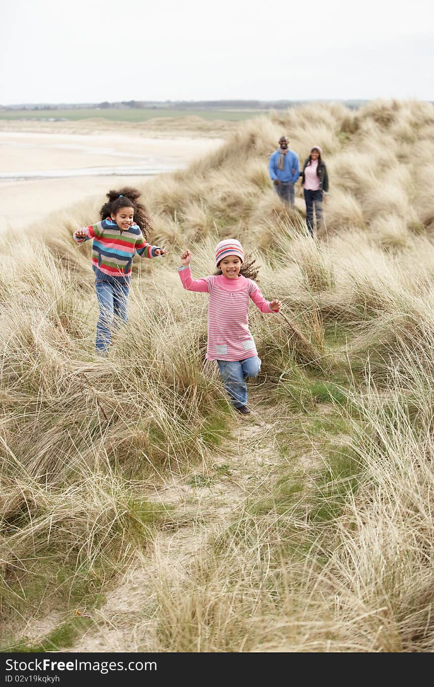 Family Walking Along Sand Dunes On Winter Beach