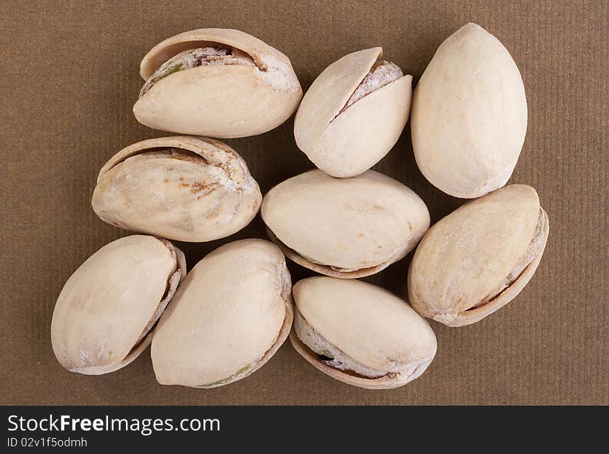 Shelled pistachios laying on a brown background.