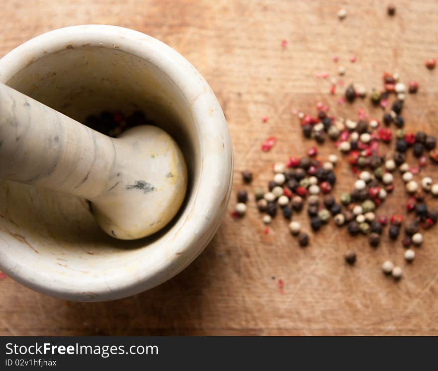 A mortar and a pestel for spices and pepper on a wooden hardboard. A mortar and a pestel for spices and pepper on a wooden hardboard