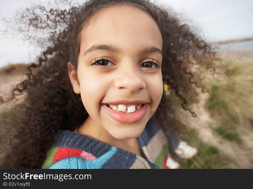 Young Girl Sitting Amongst Dunes On Winter Beach