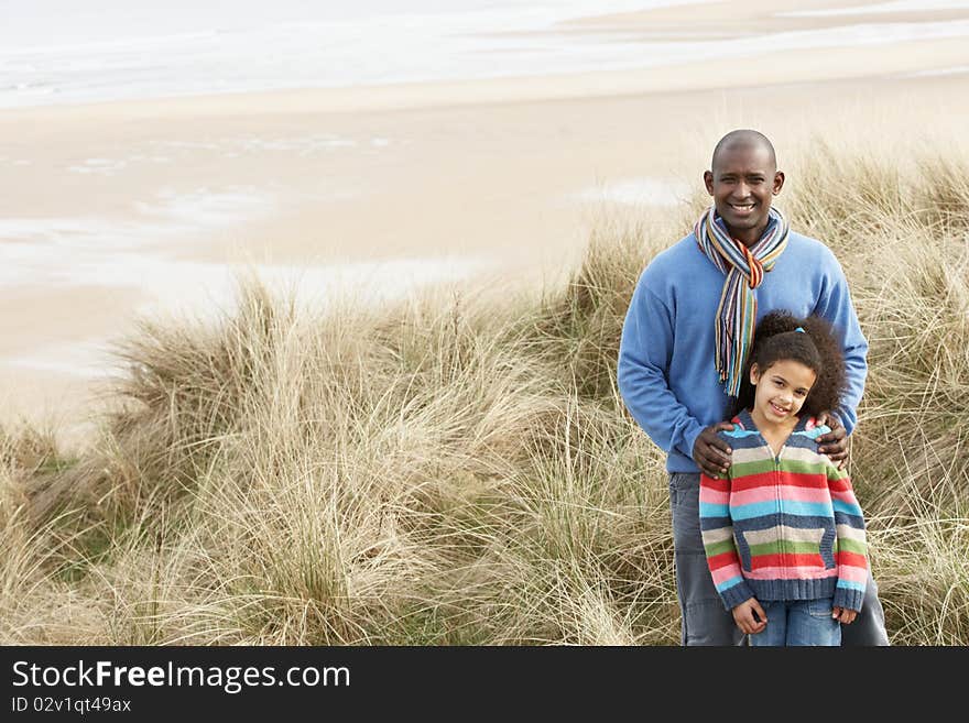 Father And Daughter Amongst Sand Dunes On Winter Beach Smiling. Father And Daughter Amongst Sand Dunes On Winter Beach Smiling