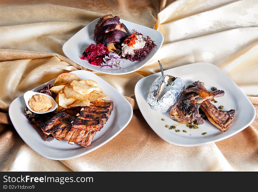 Photo of three different plates of fried meat, one with pork ribs, one with lamb fillets, and another one with pork leg joint. Photo of three different plates of fried meat, one with pork ribs, one with lamb fillets, and another one with pork leg joint.