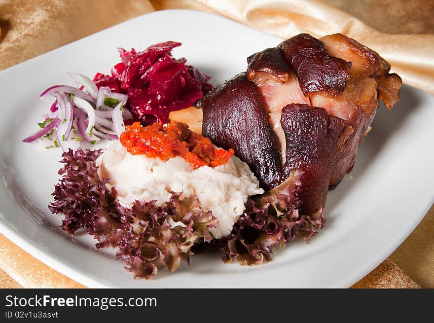 A freshly roasted leg of pork with onion, beetroot, salad and sauce. A freshly roasted leg of pork with onion, beetroot, salad and sauce.