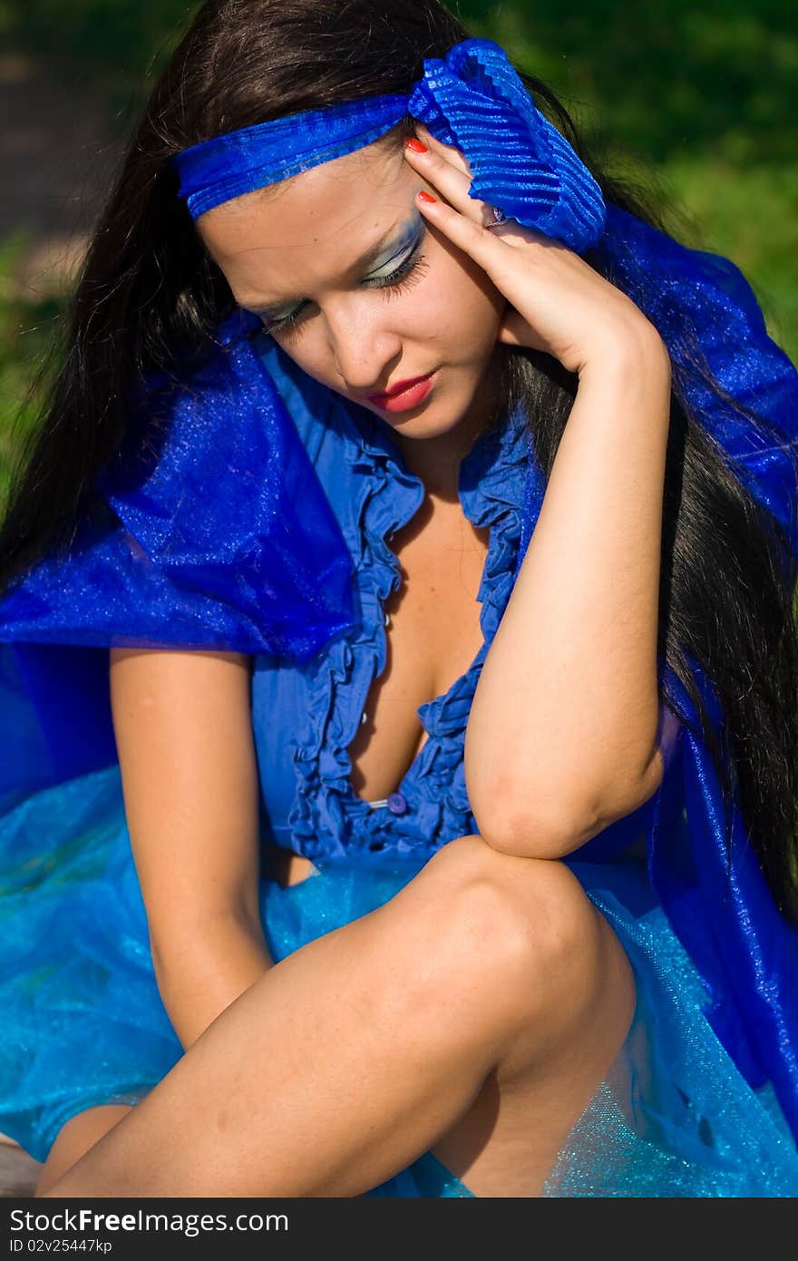 Beautiful girl with blue eyes and dark hair. Girl dressed in a blue cloth, like a dress. In her hair - burgundy flower. Beautiful girl with blue eyes and dark hair. Girl dressed in a blue cloth, like a dress. In her hair - burgundy flower