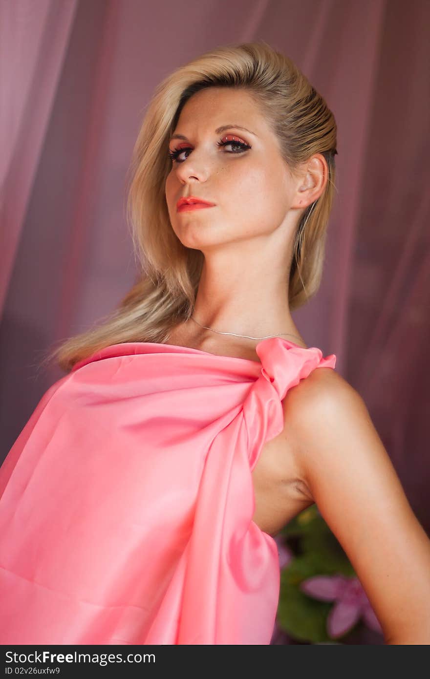 Beautiful sexy girl with blond hair and expressive eyes wearing in a pink dress. Beautiful sexy girl with blond hair and expressive eyes wearing in a pink dress