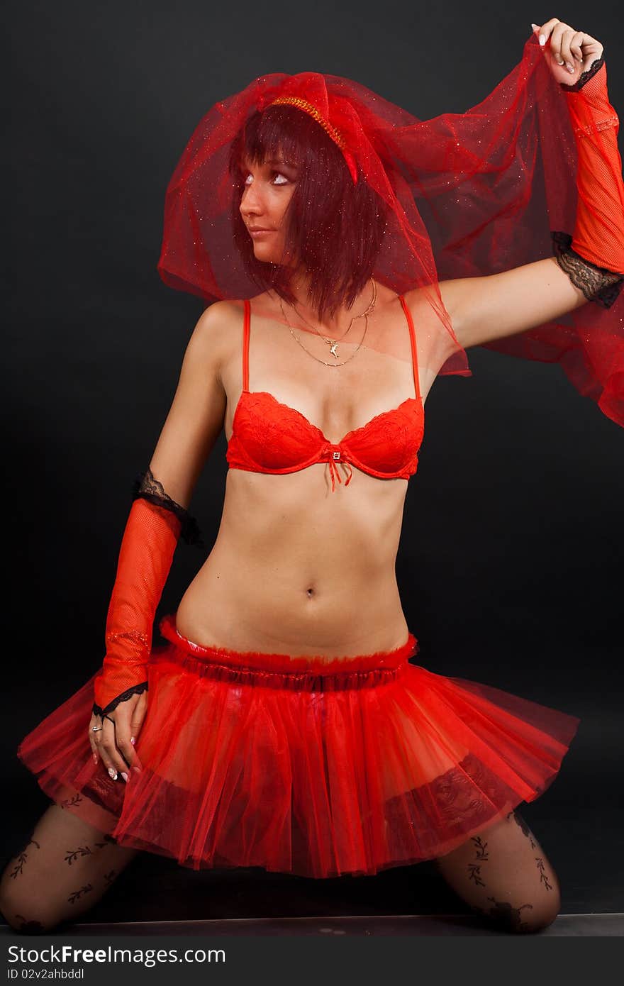 Beautiful dark-haired girl in a red wedding dress isolated on black background in studio. Beautiful dark-haired girl in a red wedding dress isolated on black background in studio