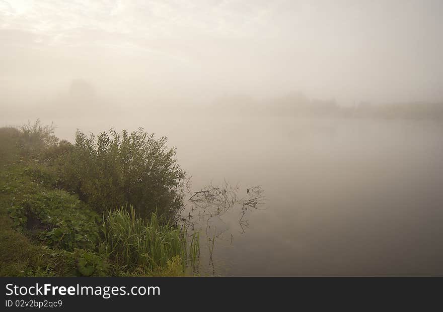 A misty early morning lake landscape with a calm water base. A misty early morning lake landscape with a calm water base