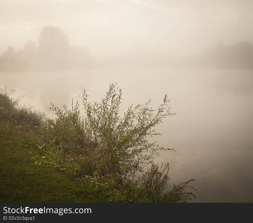 A misty early morning lake landscape with a calm water base. A misty early morning lake landscape with a calm water base