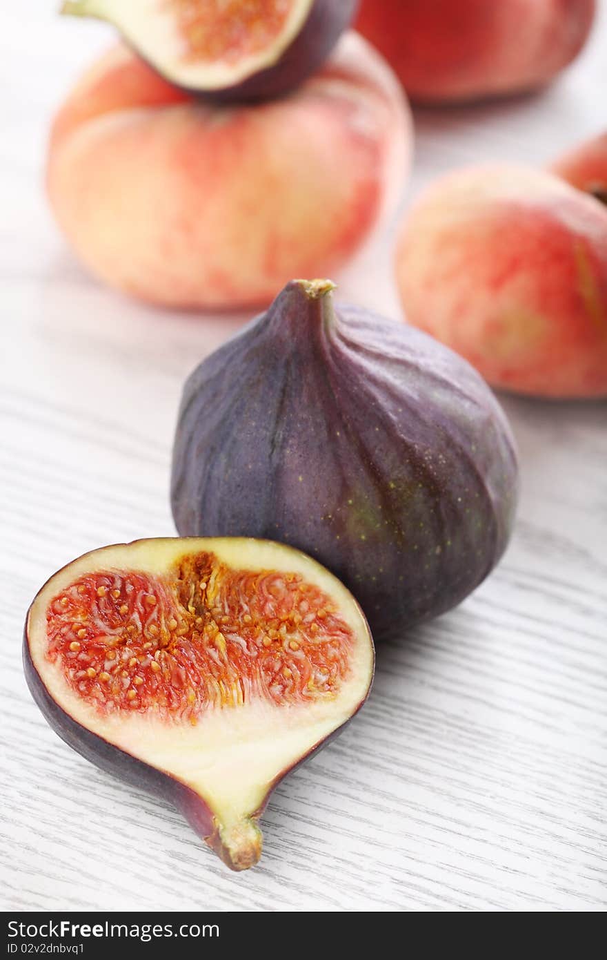 Fresh figs and peaches on the white wooden background