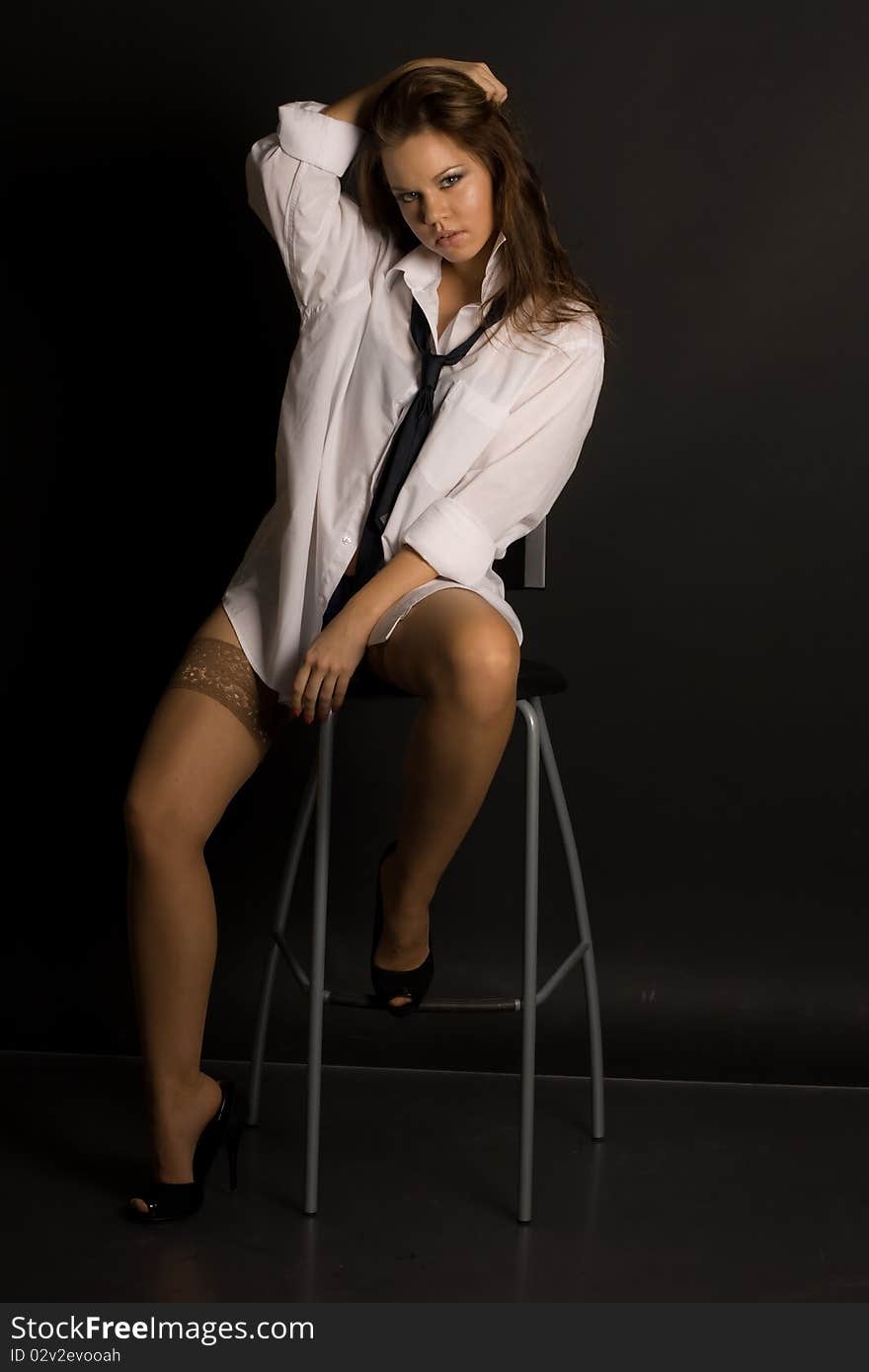 Young beautiful girl on a chair isolated on black background. Young beautiful girl on a chair isolated on black background