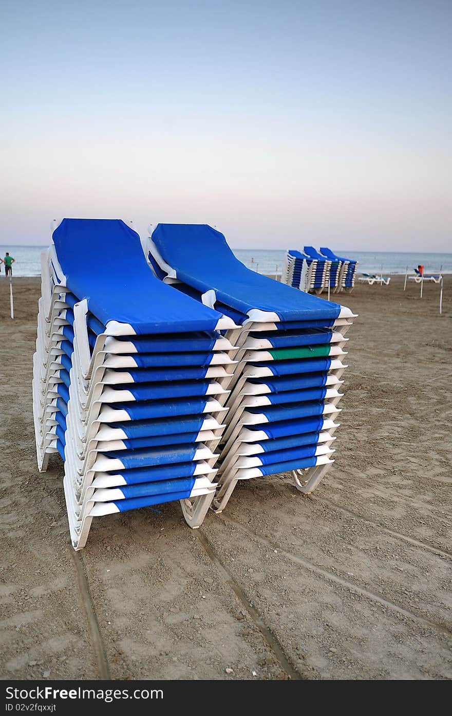 Stacked Blue Deckchairs On A Beach