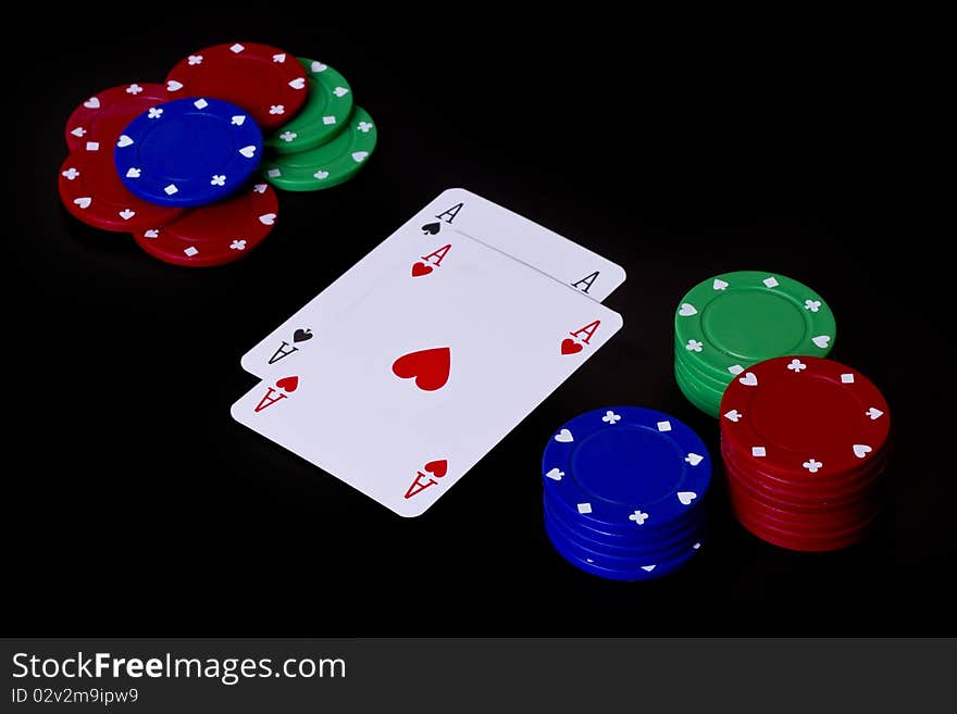 Pair of aces surrounded by gambling chips on a black background