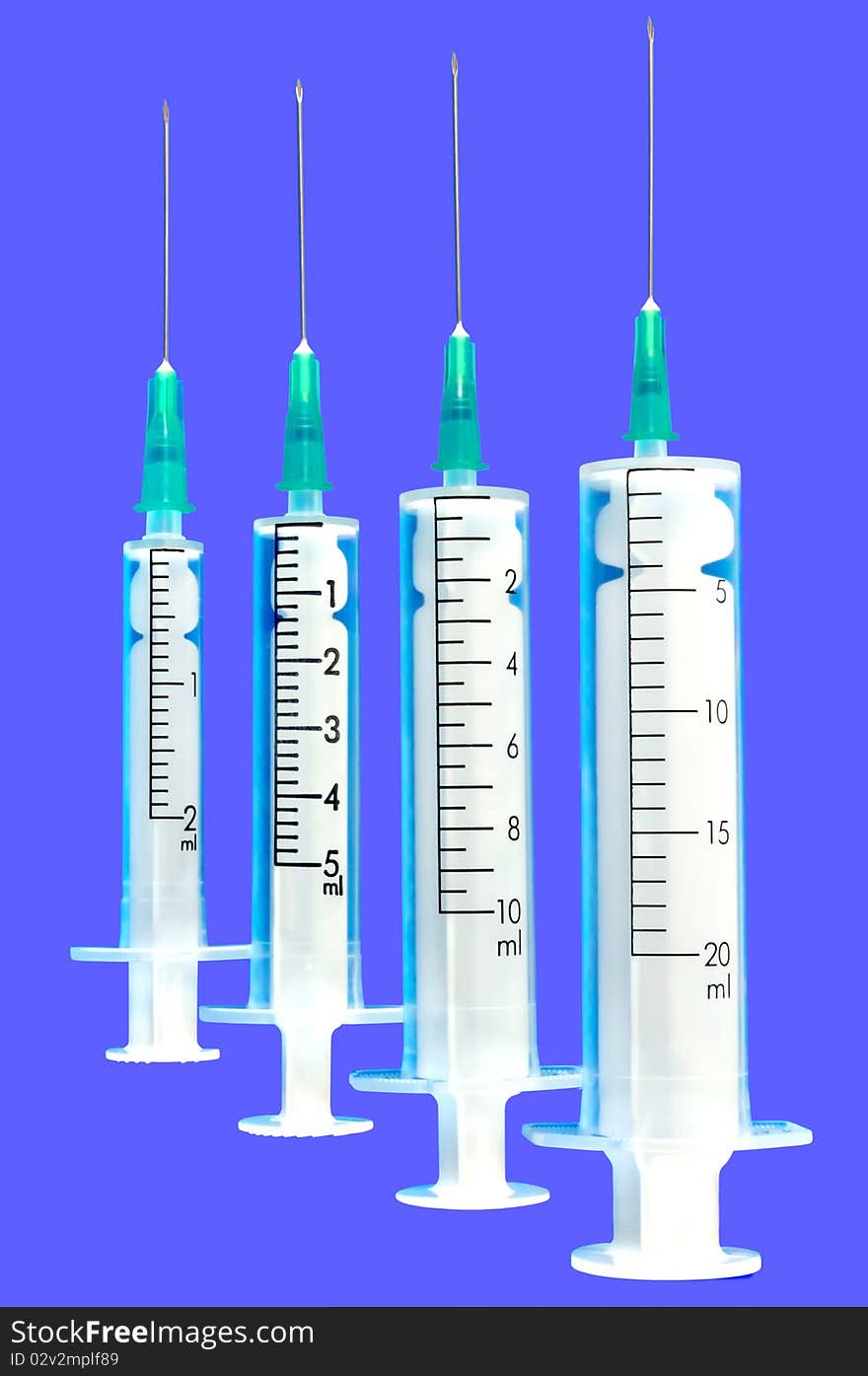 Four disposable syringe against blue background