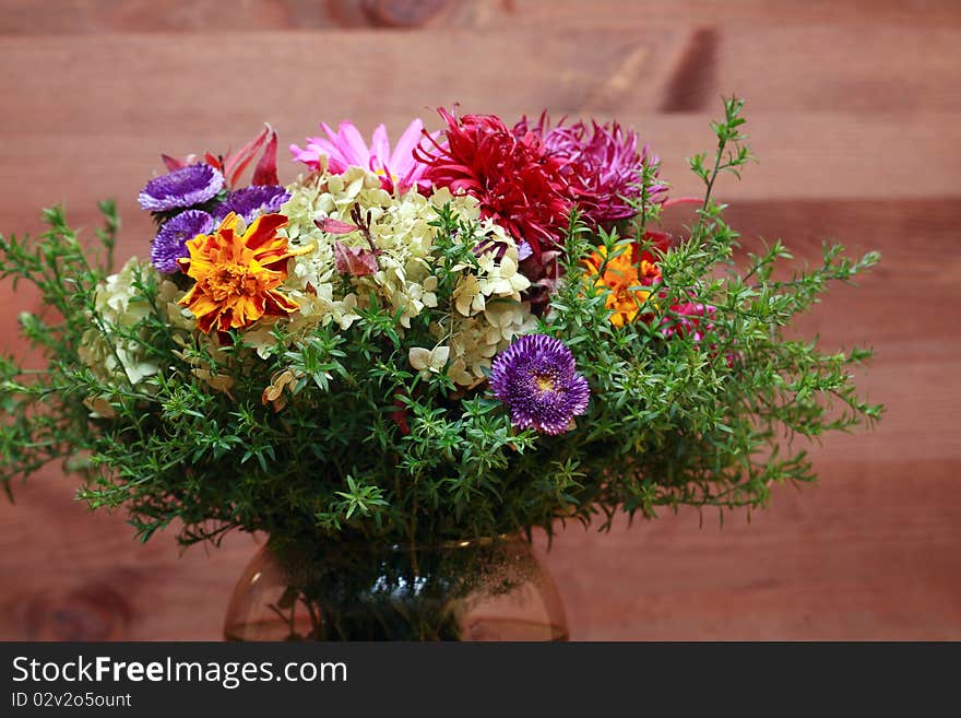 Glass vase with fresh flower bouquet on dark wooden background